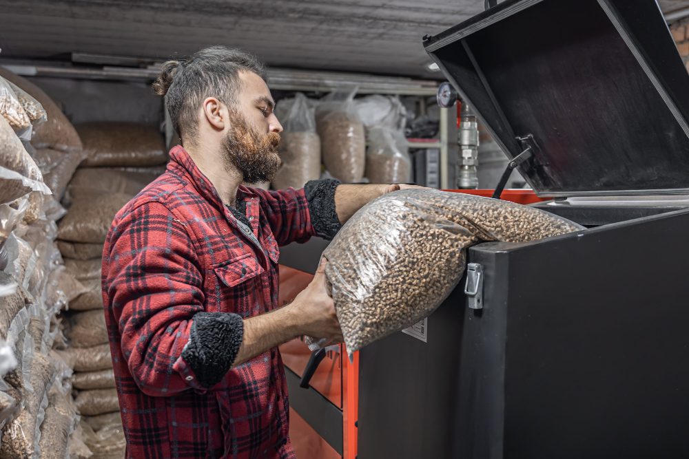 man loads pellets solid fuel boiler working with biofuels economical heating